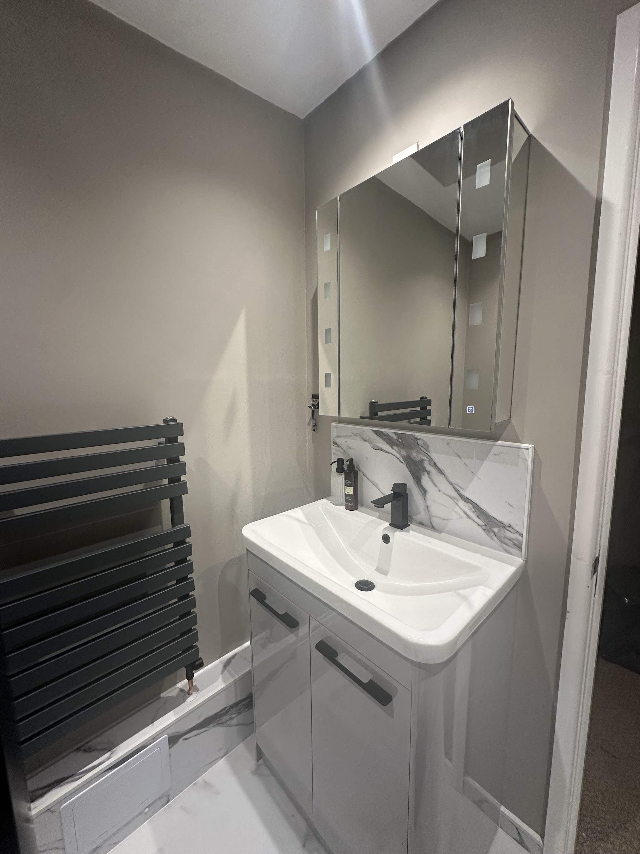 Bathroom vanity with a marble effect splashback and black towel rail