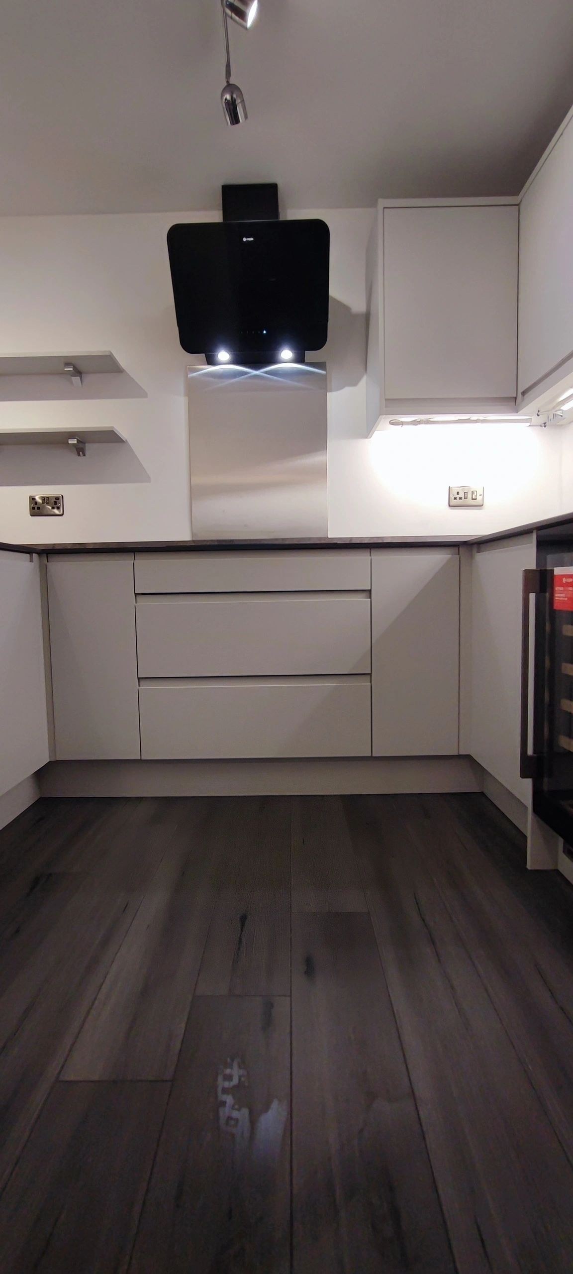 Handleless kitchen with dark flooring and black hood