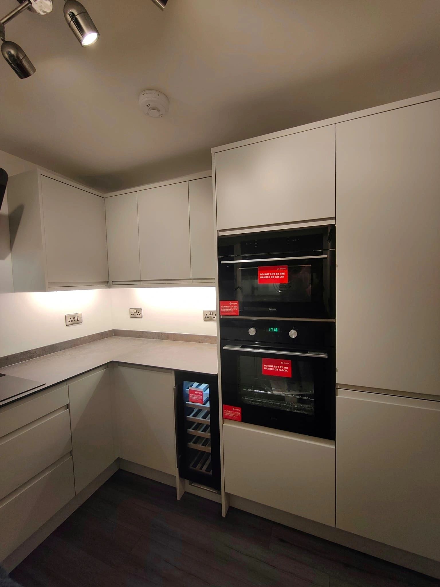 Handleless light grey kitchen with double ovens and a wine cooler