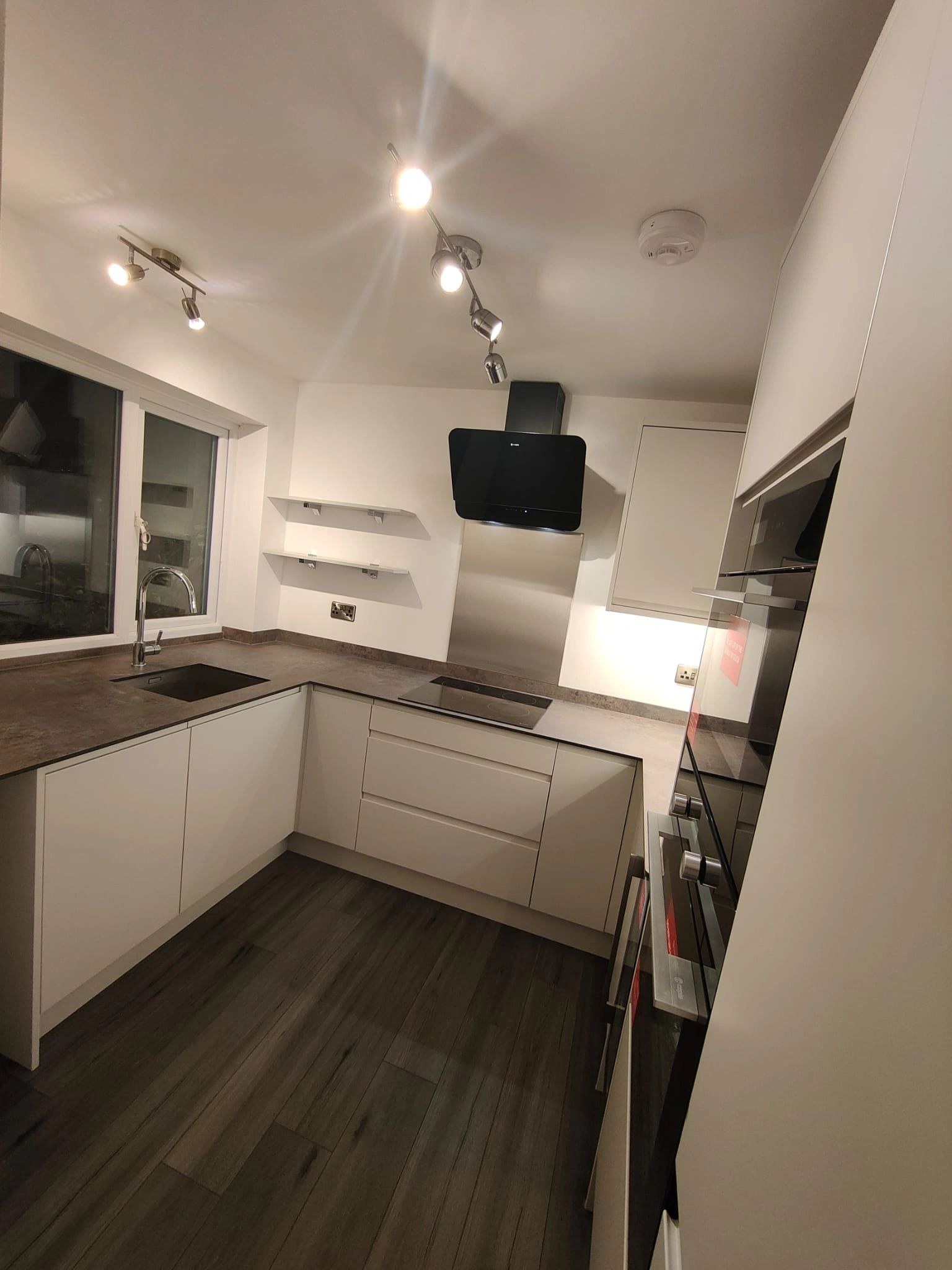 Wide view of a handleless kitchen with an angled black extractor hood