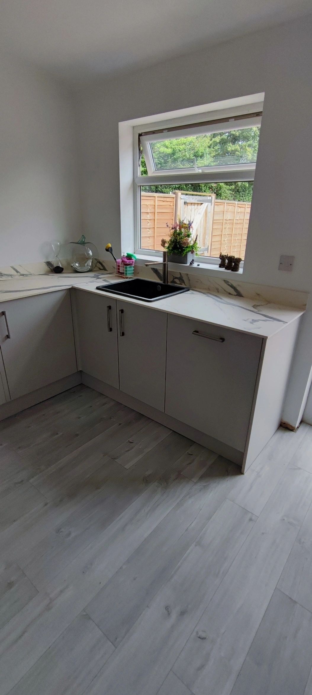 White kitchen sink run beneath the window