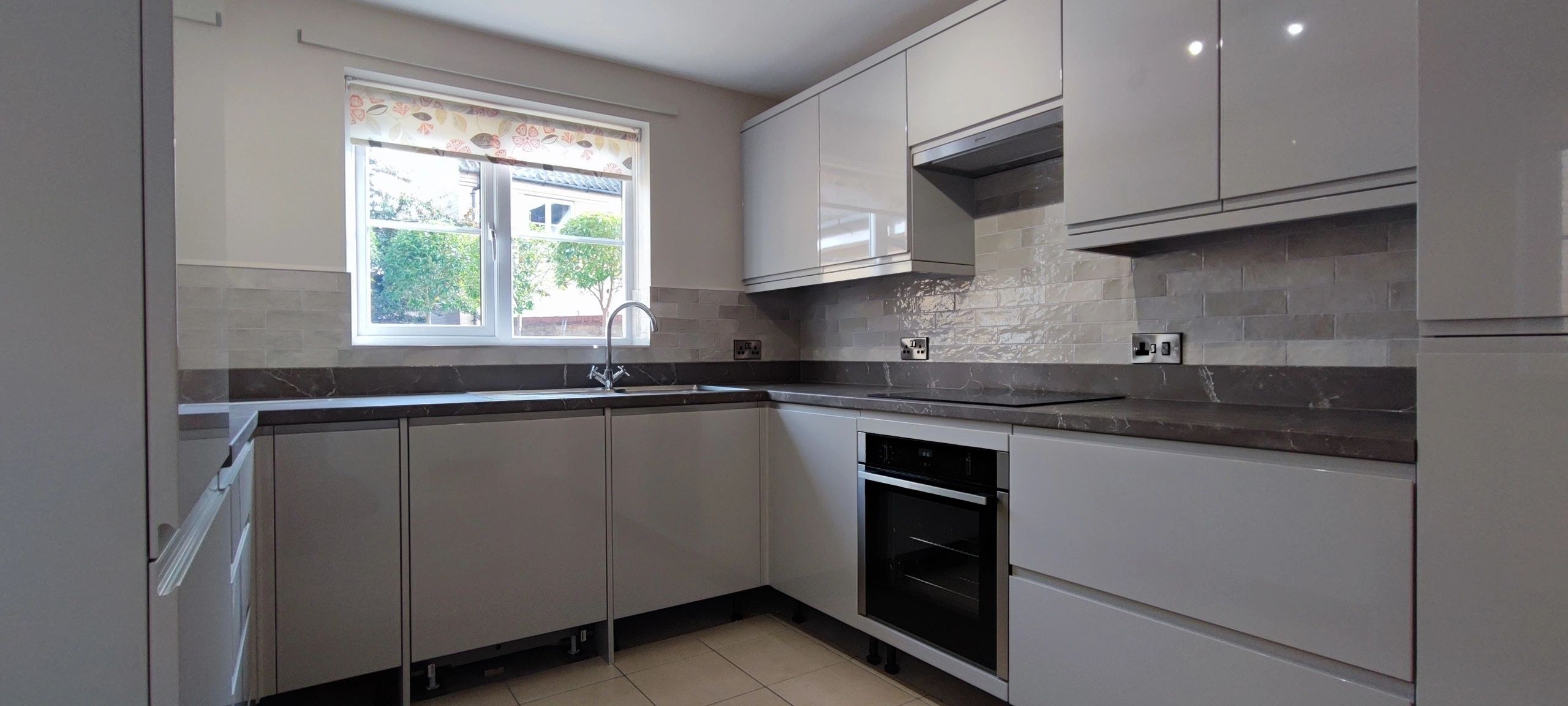 Gloss light grey L-shaped kitchen, panoramic view